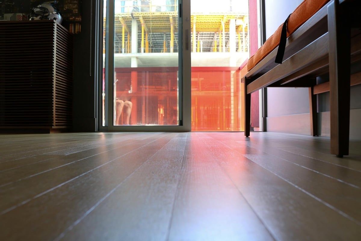 Interior view highlighting modern hardwood flooring and sunlight streaming through a glass door.